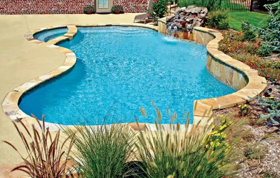 Custom freeform pool with natural rock waterfall and flagstone coping